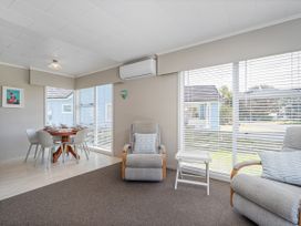 A living room with a sofa and dining table at Matarangi Holiday Home in Whitianga