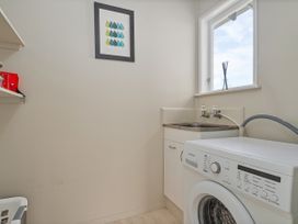 A laundry room with a washing machine and sink at Matarangi Holiday Home Whitianga