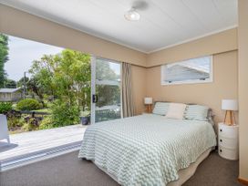 A bedroom with a bed and windows at Matarangi Holiday Home Whitianga