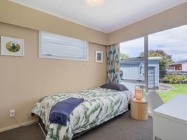 A bedroom with a bed and desk at Matarangi Holiday Home Whitianga