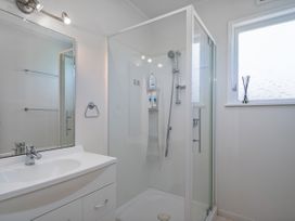 A bathroom with a shower and sink at Matarangi Holiday Home in Whitianga