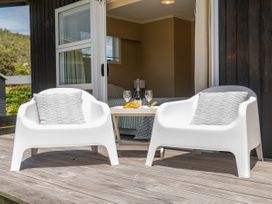 A seating area with white chairs and a table at Matarangi Holiday Home Whitianga