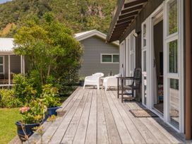 An outdoor deck with chairs and a table at Matarangi Holiday Home Whitianga