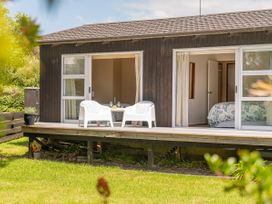 A deck with chairs and a table outside the house at Matarangi Holiday Home in Whitianga