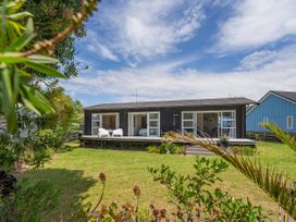 A house with a deck and chairs at Matarangi Holiday Home Whitianga