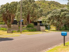An outdoor view of a road near a house with trees and a mailbox at Matarangi Holiday Home in Whitianga