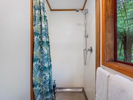 A shower with a curtain and a towel in the bathroom at The Oak House - Coromandel