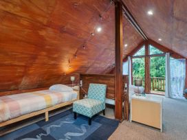 A bedroom with a bed and armchair at The Oak House - Coromandel