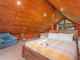 A bedroom with a bed and sofa at The Oak House - Coromandel