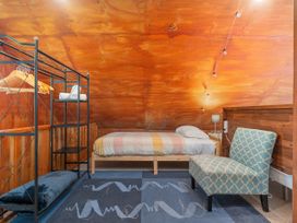 A bedroom with a bed, shelf, and chair at The Oak House - Coromandel