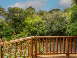A wooden balcony overlooking trees and greenery at The Oak House - Coromandel