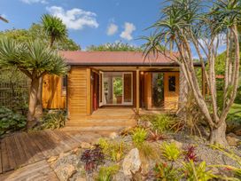 A house with plants and a wooden deck at Stream-side Cottage - Driving Creek Coromandel