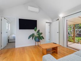 A living room with a television and sofa at Stream-side Cottage - Driving Creek Coromandel