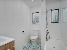 A bathroom with a toilet, sink, shower, and bathtub at Stream-side Cottage - Driving Creek Coromandel