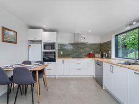 A kitchen featuring a dining table with chairs at Stream-side Cottage - Driving Creek Coromandel