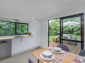 A kitchen with modern appliances and a dining area at Stream-side Cottage - Driving Creek Coromandel