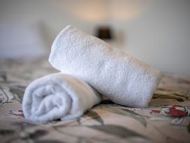 Two rolled towels on a bed at Te Anau Holiday Home in Te Anau