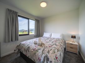 A bedroom with a bed, curtains, and a window at Te Anau Holiday Home in Te Anau