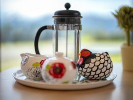 A tray with a french press, cream jug, sugar bowl, and decorative chicken at Te Anau Holiday Home in Te Anau