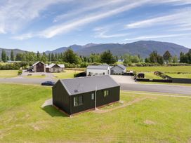An outdoor view of a black house near mountains at Te Anau Holiday Home Te Anau