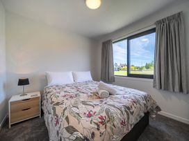 A bedroom with a bed and bedside table at Te Anau Holiday Home in Te Anau