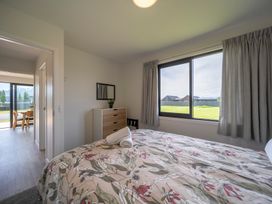 A bedroom with a bed and window at Te Anau Holiday Home in Te Anau