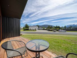 A deck with a table and chairs overlooking a street at Te Anau Holiday Home in Te Anau