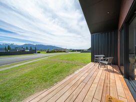 An outdoor area with a wooden deck and chairs at Te Anau Holiday Home Te Anau