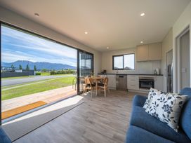 A living room with a sofa and dining area at Te Anau Holiday Home in Te Anau