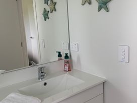 A bathroom with a sink and mirror at Glaisnock Hut - Te Anau Holiday Home