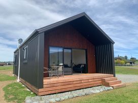 A house with a porch and windows at Glaisnock Hut - Te Anau Holiday Home Te Anau