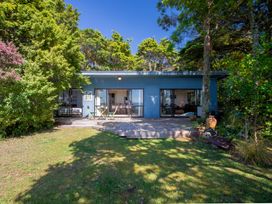 A house with a deck surrounded by trees at Seabreeze Hideaway - Golden Bay Holiday Home in Collingwood