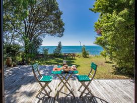A table with chairs and a tea set overlooking the water at Seabreeze Hideaway - Golden Bay Holiday Home, Collingwood