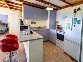 A kitchen with bar stools and appliances at Seabreeze Hideaway - Golden Bay Holiday Home in Collingwood