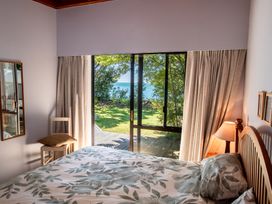 A bedroom with a bed and view of the garden at Seabreeze Hideaway - Golden Bay Holiday Home, Collingwood