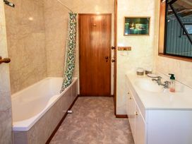 A bathroom featuring a bathtub, sink and wooden door at Seabreeze Hideaway - Golden Bay Holiday Home, Collingwood