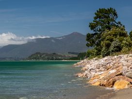 A shoreline with trees and mountains at Seabreeze Hideaway - Golden Bay Holiday Home Collingwood