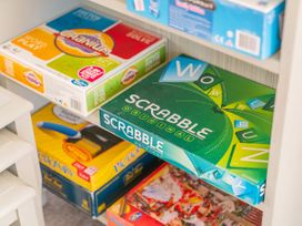 A shelf with various board games including SCRABBLE at Cozy Cottage - Whitianga Holiday Home Whitianga