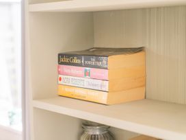 A shelf with books and a jar at Cozy Cottage - Whitianga Holiday Home, Whitianga
