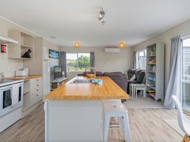 A kitchen with appliances and seating area at Cozy Cottage - Whitianga Holiday Home Whitianga