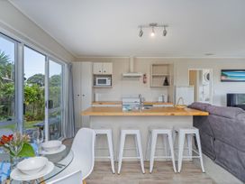 A kitchen with counter and stools at Cozy Cottage - Whitianga Holiday Home in Whitianga