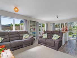 A living room with a sofa and bookshelf at Cozy Cottage - Whitianga Holiday Home in Whitianga