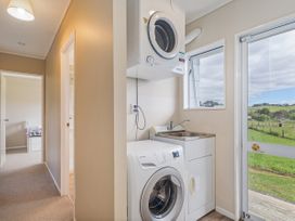 A laundry room with a washing machine, dryer, and sink at Cozy Cottage - Whitianga Holiday Home Whitianga