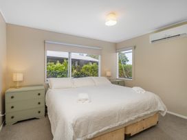 A bedroom with a bed and a nightstand with a lamp at Cozy Cottage - Whitianga Holiday Home in Whitianga