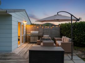 An outdoor seating area with a grill and umbrella at Cozy Cottage - Whitianga Holiday Home in Whitianga