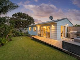 An outdoor view of a house with a deck and grill at Cozy Cottage - Whitianga Holiday Home in Whitianga