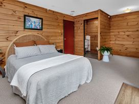 A bedroom with a bed and door leading to a bathroom at Matapouri Holiday Home Whangarei