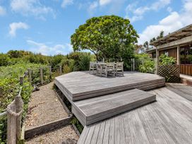 An outdoor deck with seating and a tree at Matapouri Holiday Home in Whangarei