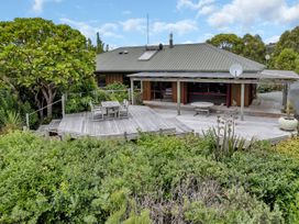 A house with a deck and dining area at Matapouri Holiday Home in Whangarei