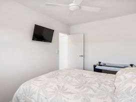 A bedroom with a bed and television at Happy Place - Waihi Beach Holiday Home in Waihi Beach